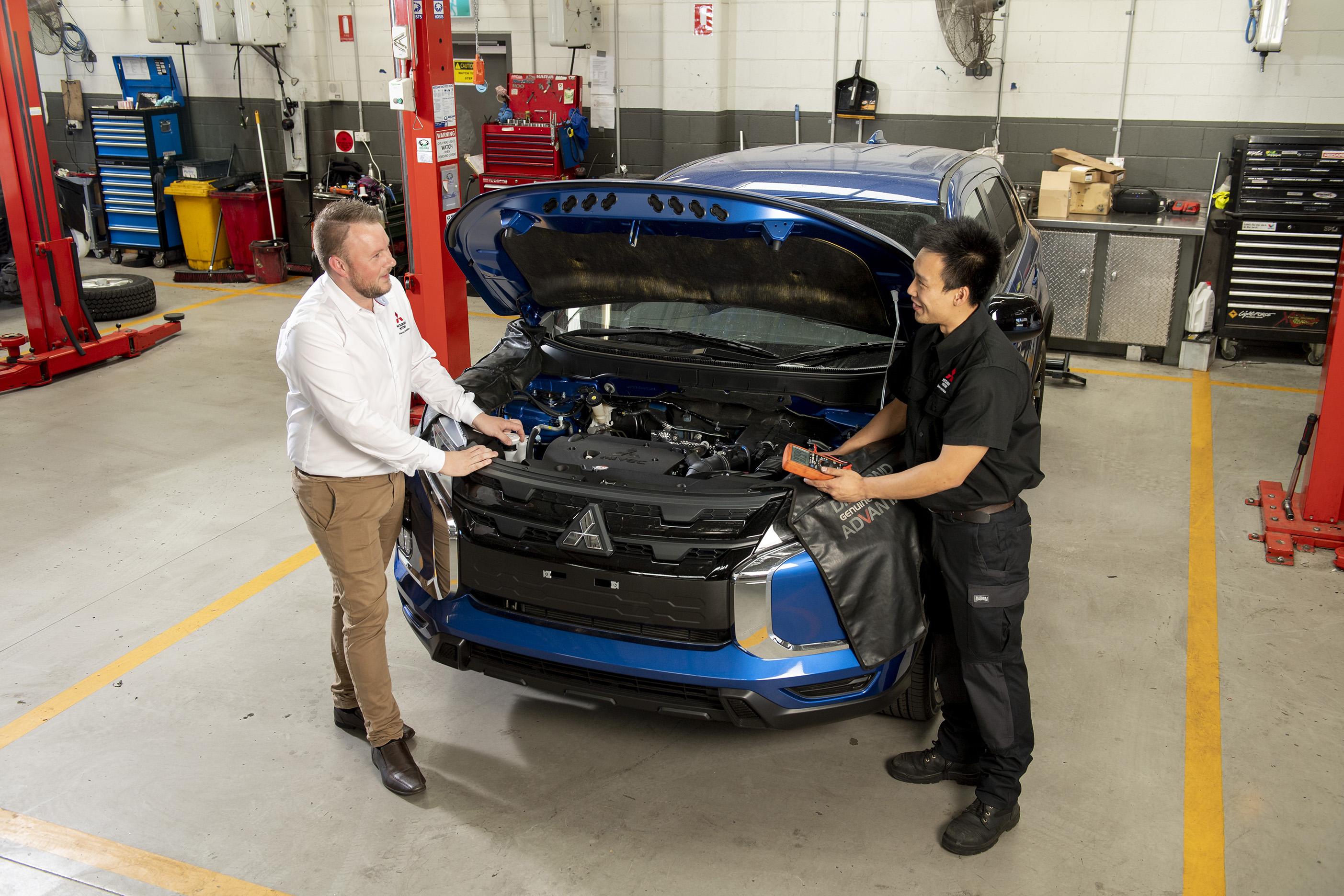 Técnico inspeccionando los frenos de un vehículo Mitsubishi en el área de servicio